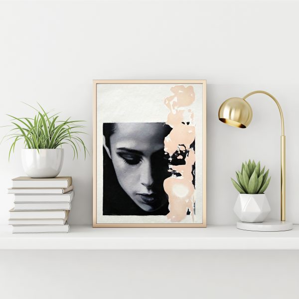 "Black and white serie 15" modern portrait with pink textured line with gold metal frame standing on the table with succulent plant, lamp and pile of books on empty white wall background.